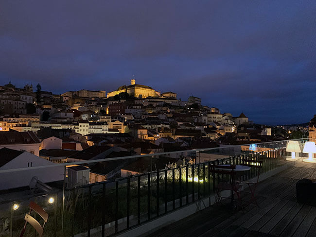 La espectacular Universidad de Coimbra iluminada de noche desde la terraza del Hotel Oslo